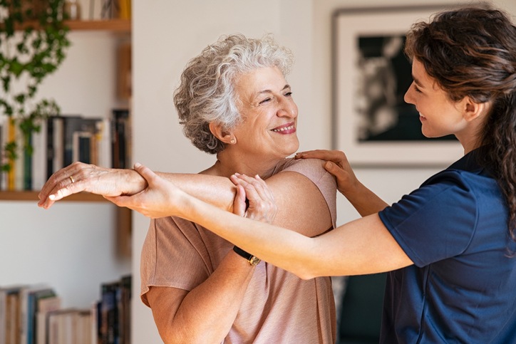 Happy senior woman doing a stretching exercise at Spring Lake Skilled Nursing and Rehabilitation with a physical therapist