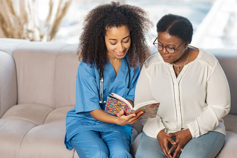 A nurse shows a journal to a patient in her room at a skilled nursing facility in Spring Lake, LA