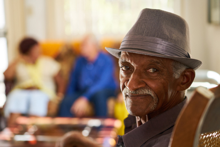A senior man with a grey hat sits in a nursing home lobby in Spring Lake, LA