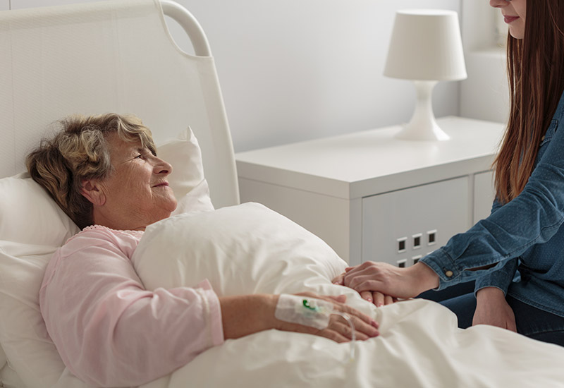 A hospice patient in Shreveport lies in bed while her granddaughter visits