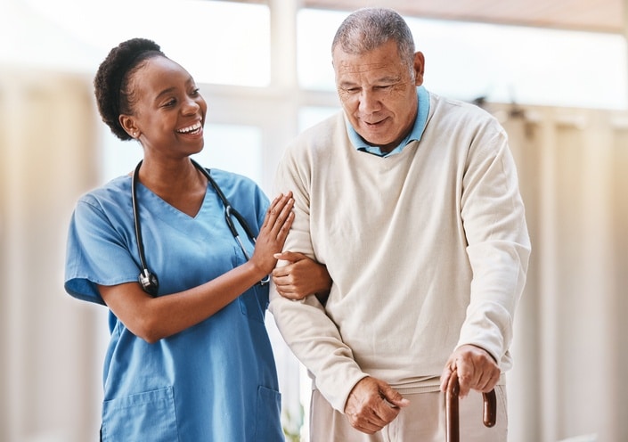 Caregiver assisting a senior man using a cane