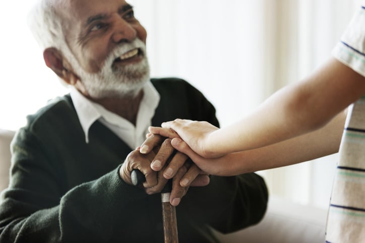 Senior man smiling and holding hands with his grandchild